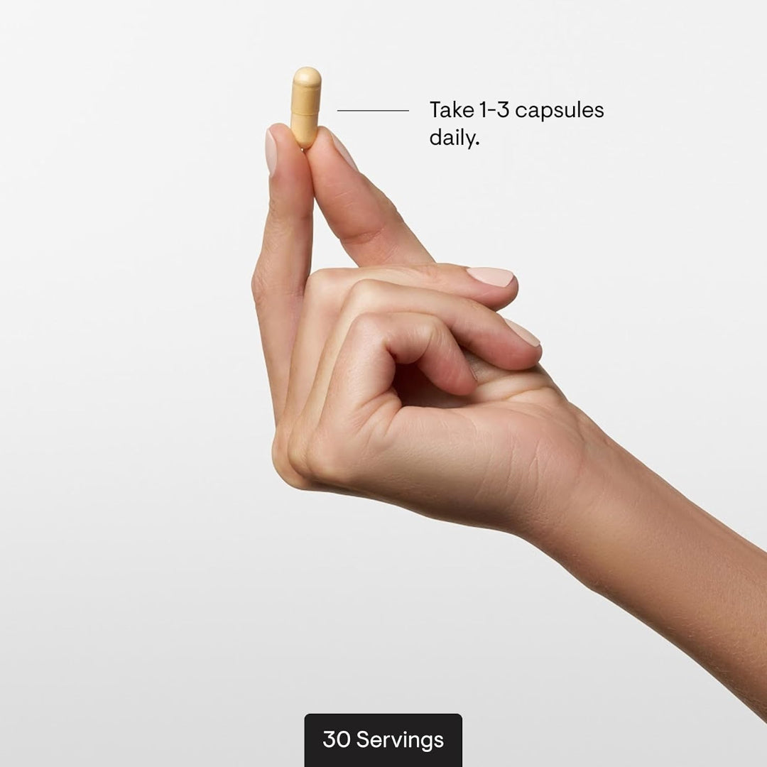 Hand holding a capsule with text indicating daily consumption and servings on a light background