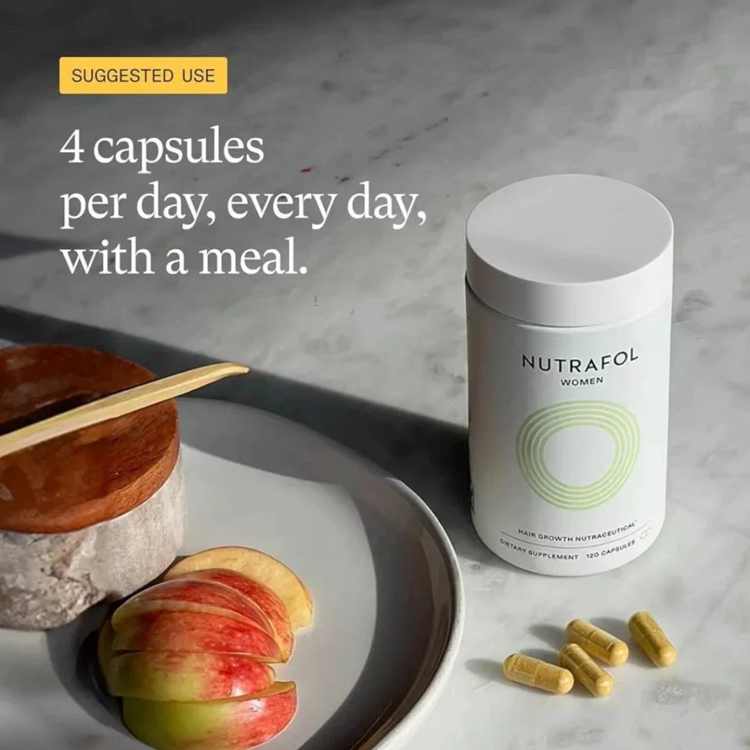 Nutrafol supplement container with capsules and apples on a marble surface
